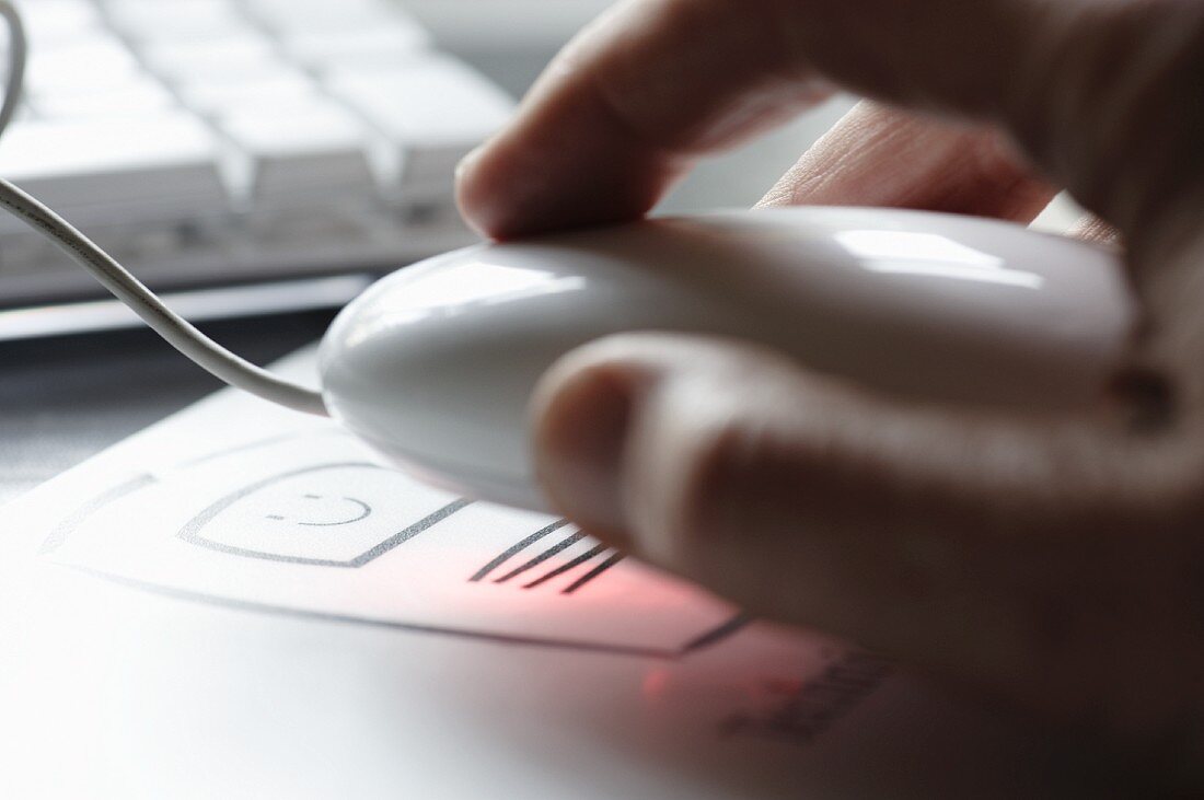 Hand on computer mouse with keyboard in background