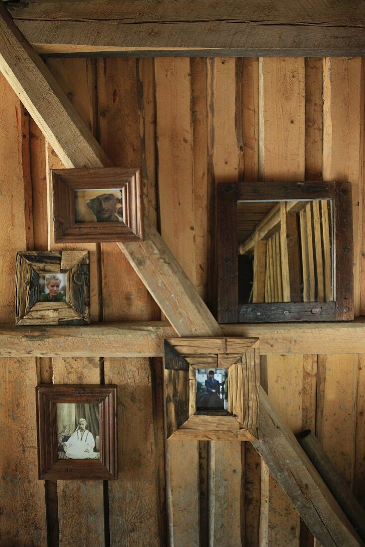Fotos mit Holzrahmen an Wand und an Holzbalken in einer Hütte