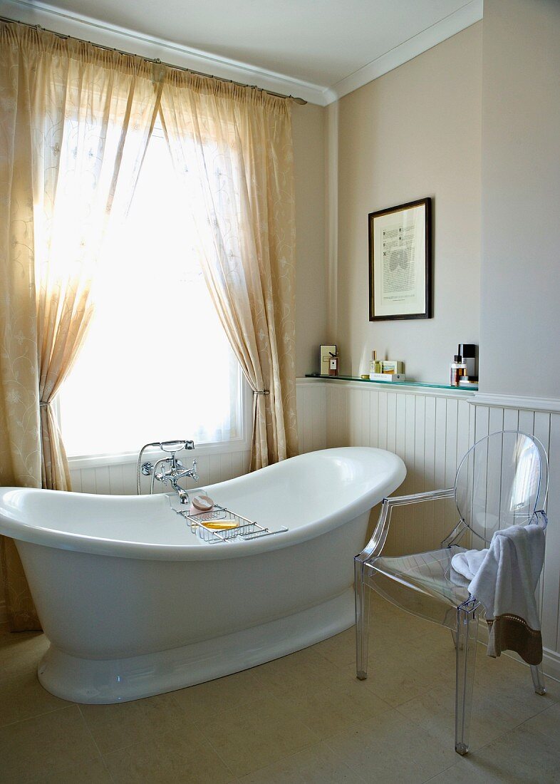 Freestanding bathtub in a traditional bathroom with modern plexiglass chair