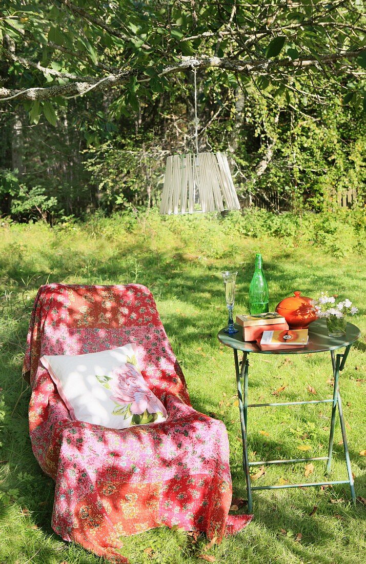 Throw on comfortable chair and garden table in shade of a tree