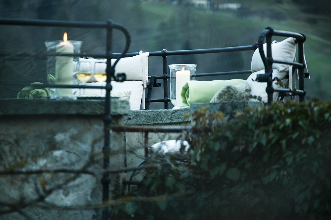 Romantic seating area - cushions and candles on stone benches surrounded by wrought iron balustrades (Schloss Schauenstein)