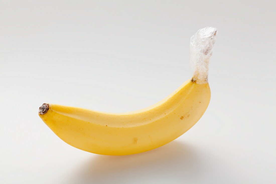 Eine Banane, der Strunk in Frischhaltefolie eingewickelt (länger haltbar)
