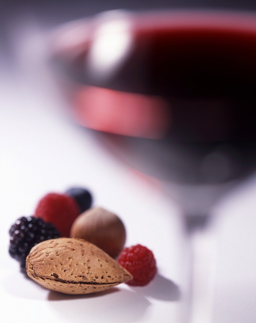 A glass of red wine with berries and nuts