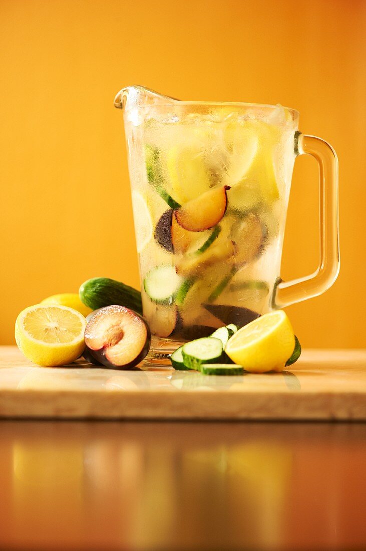 Fruchtiger Wodka-Cocktail in einem Glaskrug, daneben frische Früchte