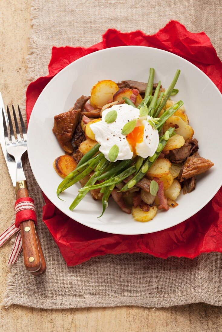 Tiroler Gröstl mit Kartoffeln, Schweinefleisch, grünen Bohnen und pochiertem Ei