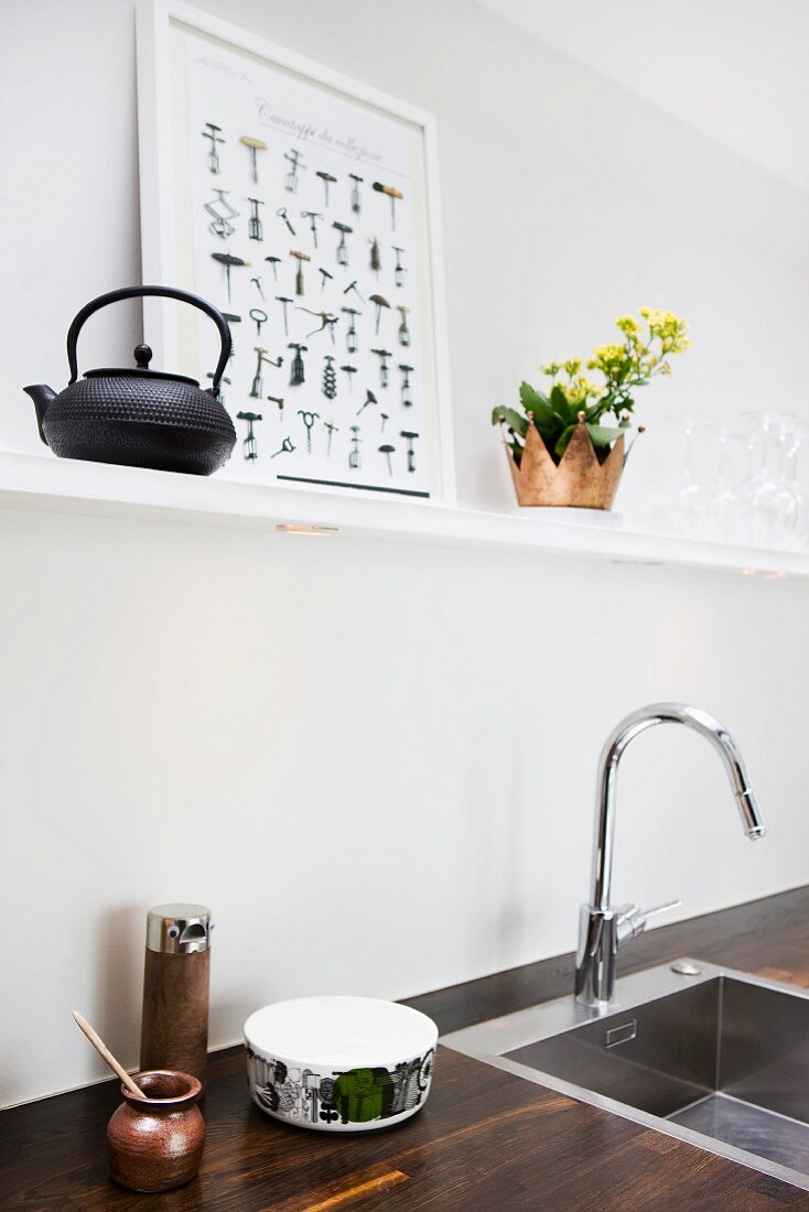 Wooden worksurface with recessed sink and designer tap fitting below white shelf