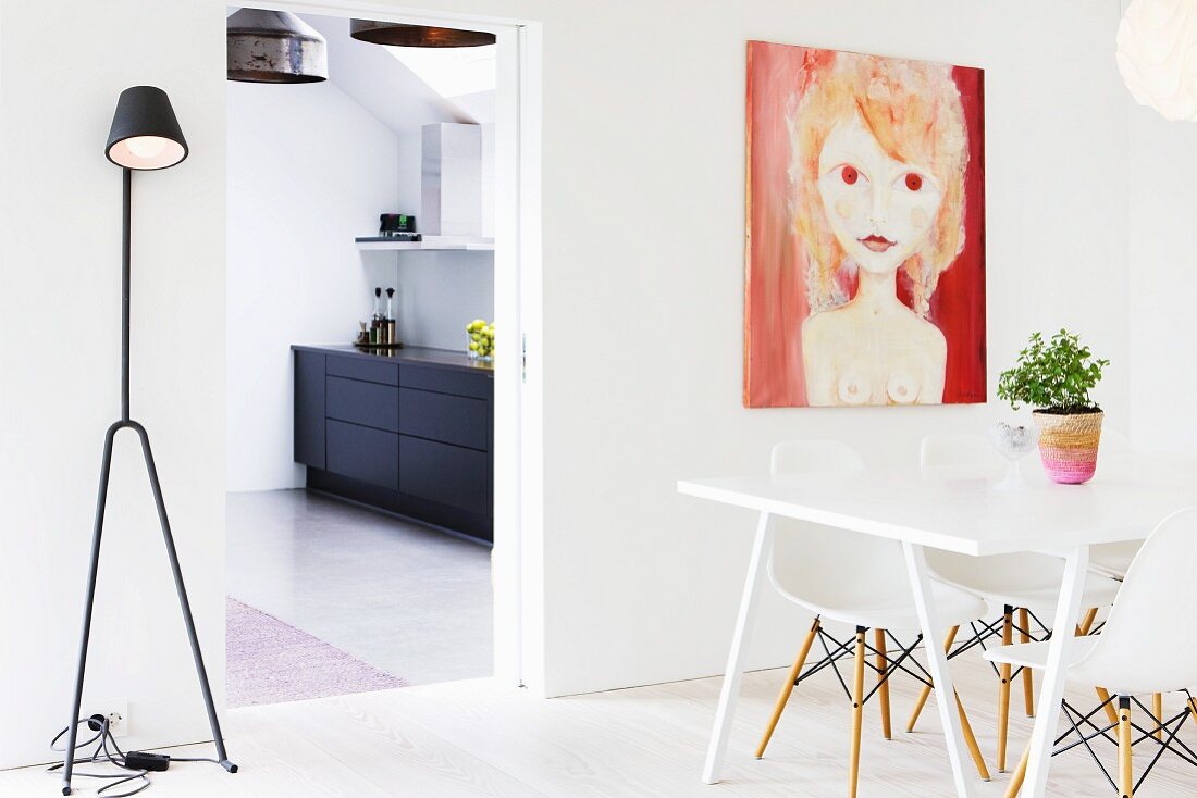 Essplatz mit Bauhausstühlen gegenüber modernem Bild an Wand und Stehleuchte neben offenem Türdurchgang mit Blick in die Küche