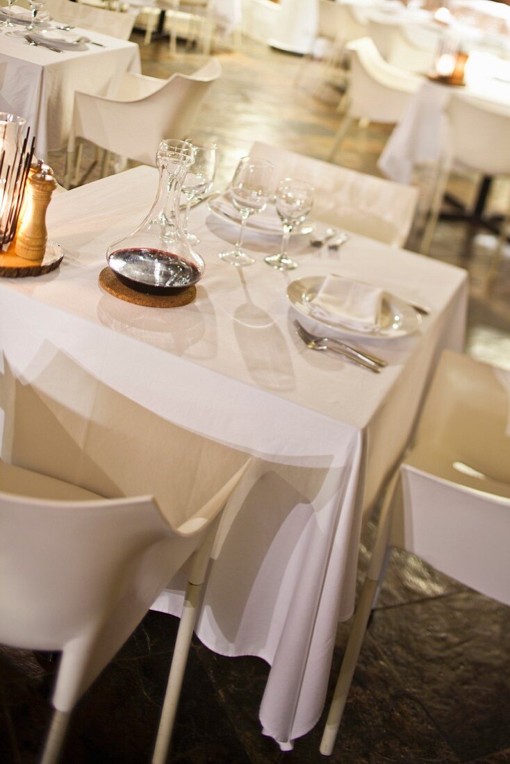 Gedeckter Tisch im Speisesaal mit weißer Tischdecke und weißen Designerstühlen