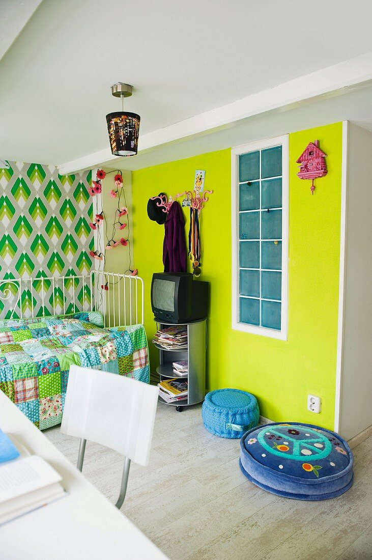 Original child's bedroom with patchwork blanket and retro wallpaper next to yellow-painted wall