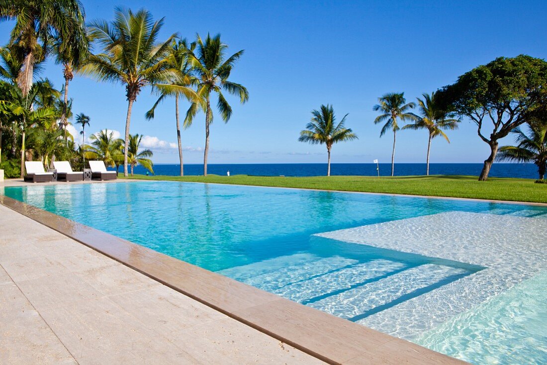 View past steps leading down into elongated pool to palm trees and Caribbean sea