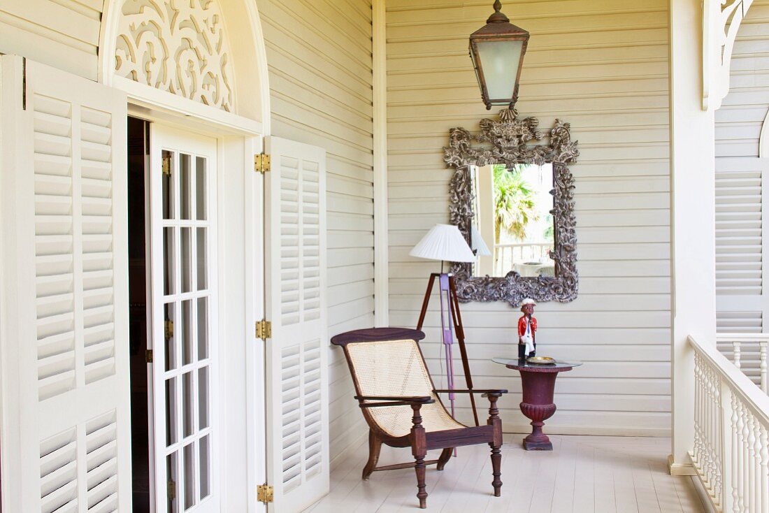 Antique armchair on white veranda; open lattice door with rounded arch above