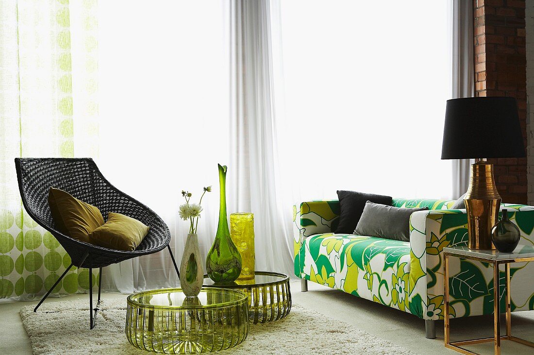 Flower power sofa, retro wicker chair and vases arranged on round side tables