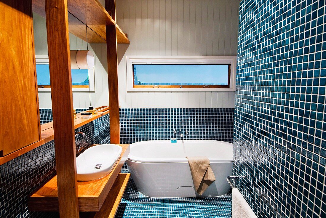 Blue mosaic tiles and washstand with exotic wood fixtures in bathroom