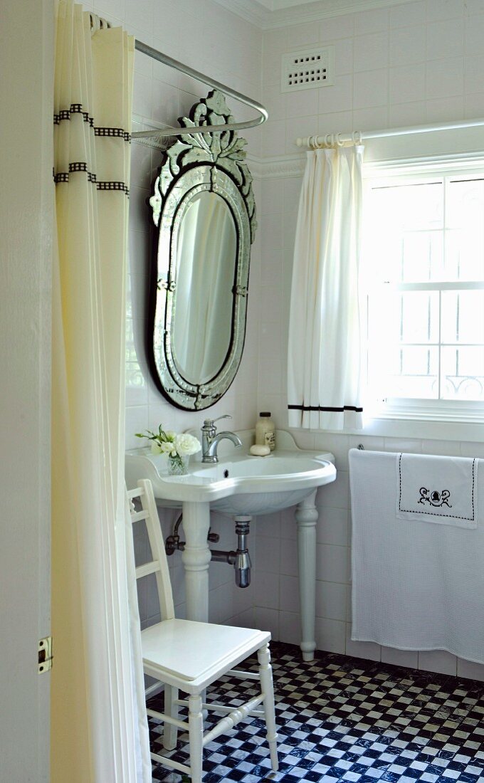 Opulent mirror above a bathroom sink in a small bathroom with checkerboard tile floor