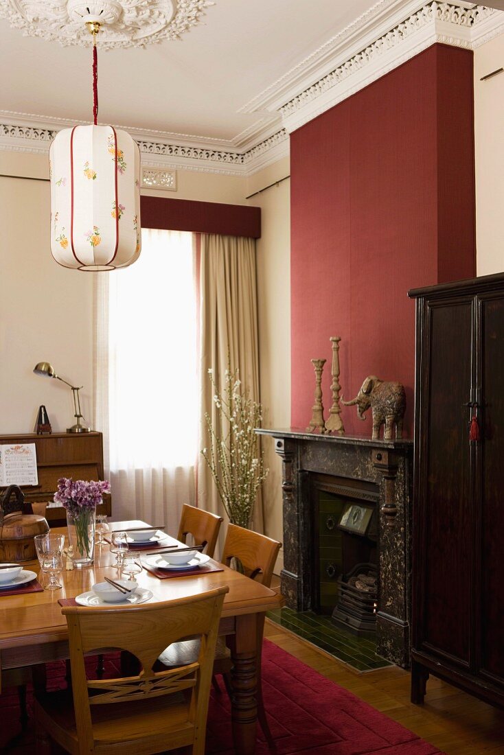 Set dining table and open fireplace in burgundy chimney breast in grand dining room with stucco ceiling