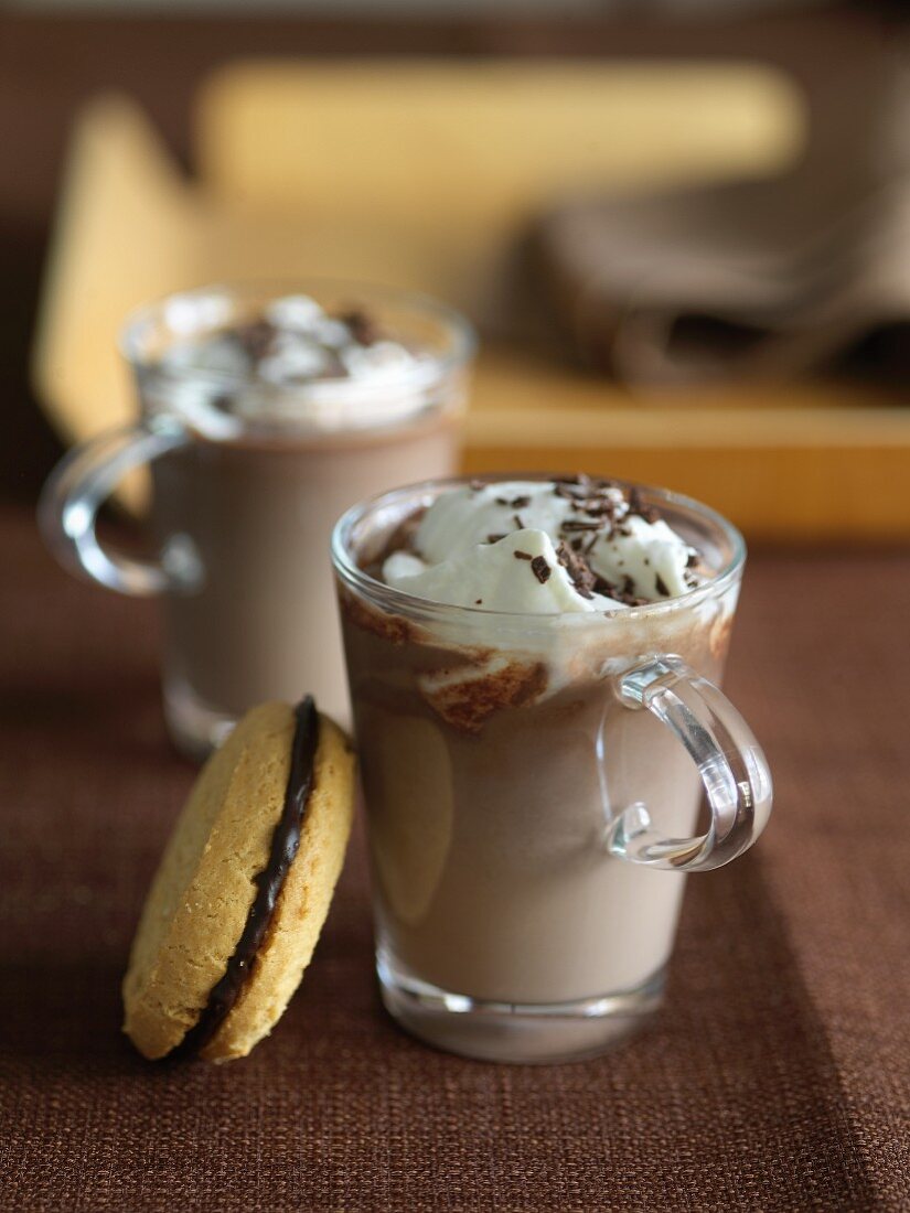 Two Cups of Hot Chocolate with Whipped Cream; Chocolate Filled Sandwich Cookie
