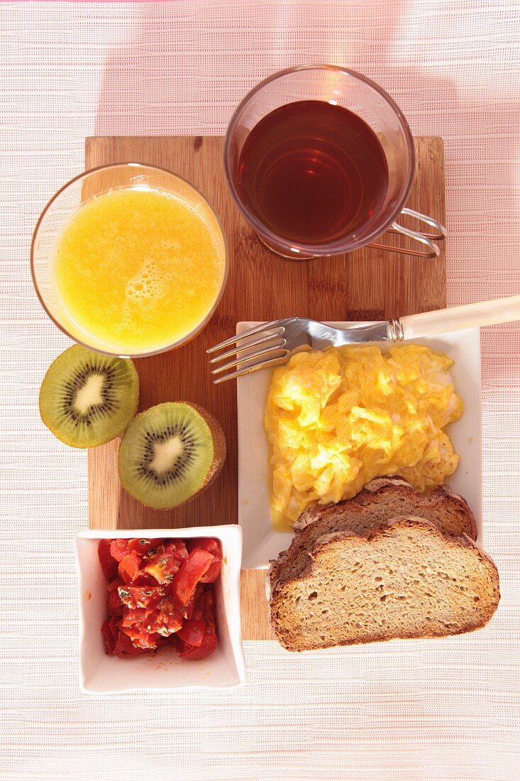 Frühstück mit Orangensaft, Tee, Rührei und Obst