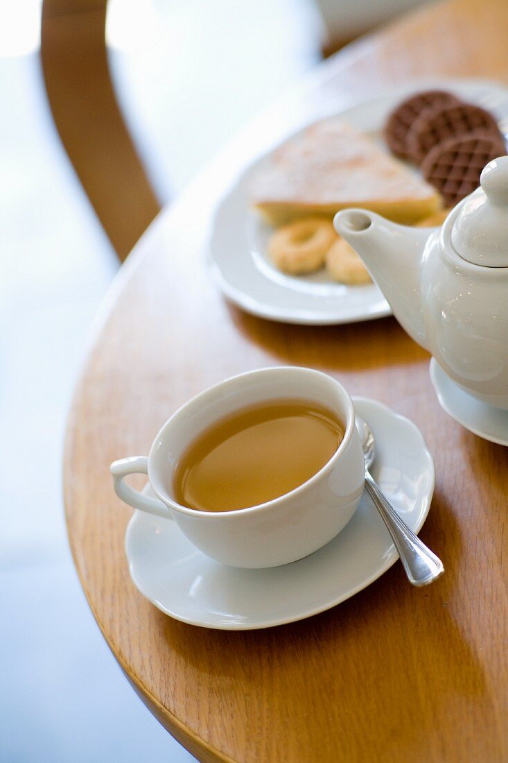 A tea still life with a cup of tea and a plate of cakes and biscuits