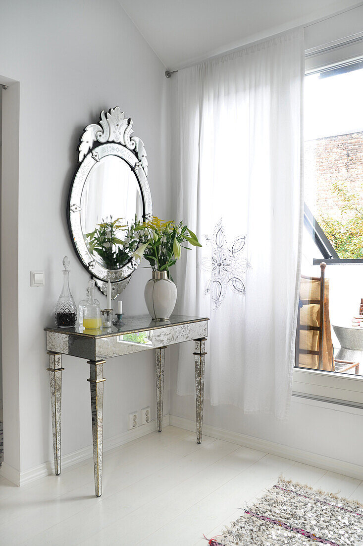 Console with bouquet of flowers, with Venetian wall mirror in corner of room