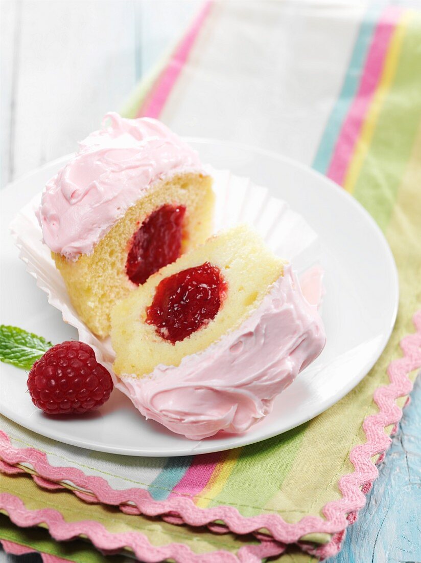 Vanilla cupcake with raspberry jam center and pink frosting