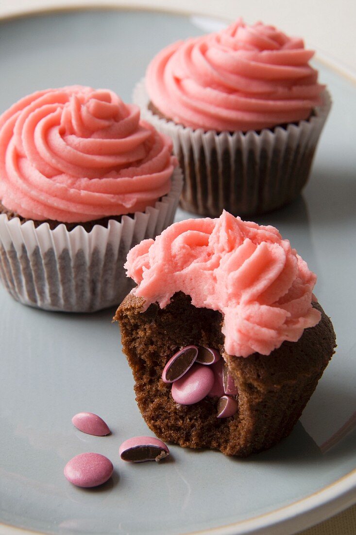 Schokoladen-Cupcakes mit rosa Schokolinsen und Frosting