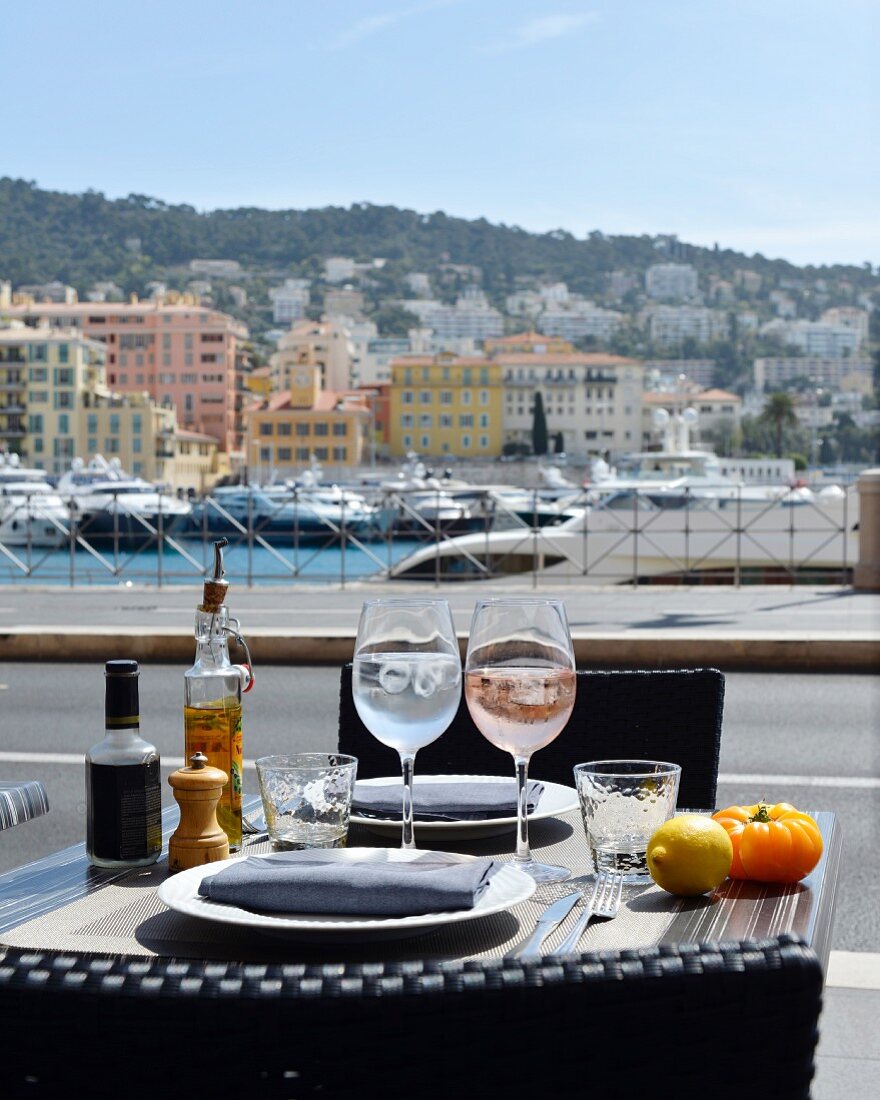 A table laid for two, with wine glasses, in a bistro on the harbour in Nice