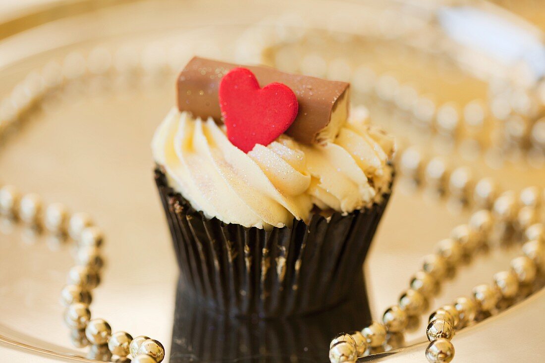 Cupcake auf goldenem Teller mit Perlenschnüren