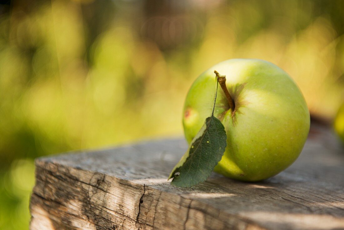 An apple on a wooden surface outdoors