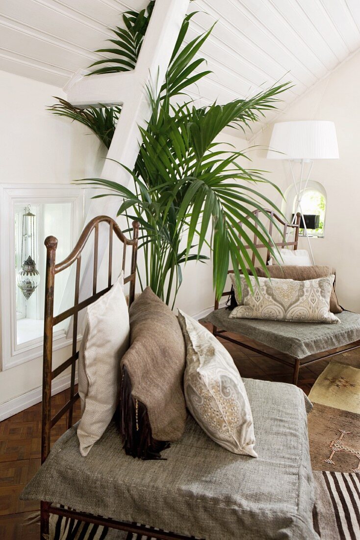 Seat cushion and scatter cushions on metal chairs in interior with white, wood-clad roof structure