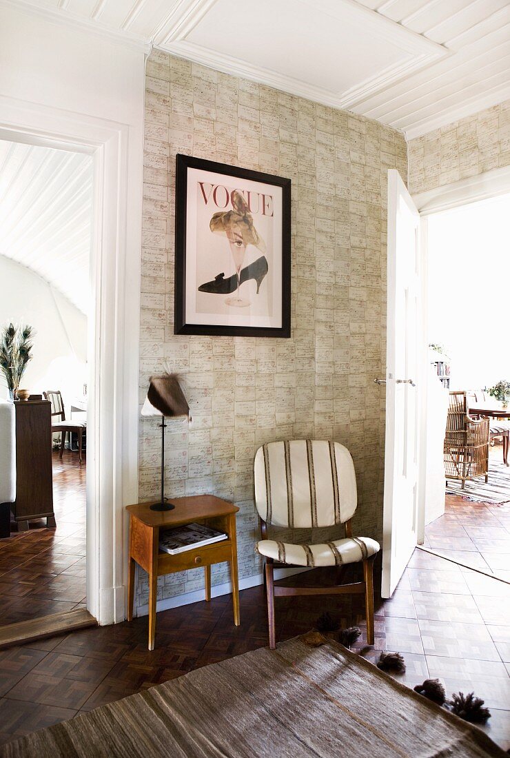 Stone-patterned wallpaper behind retro chair and retro telephone table; foyer with view through two open doors