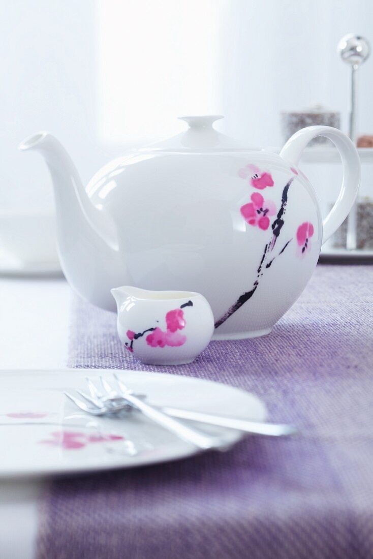 Teekanne, Milchkännchen und Teller mit Blütenmotiv