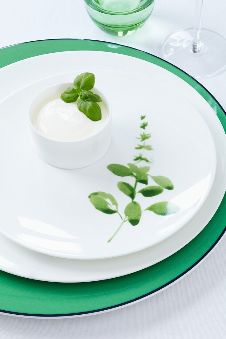 A plate decorated with a basil motif, and a small bowl of crème fraîche topped with basil leaves