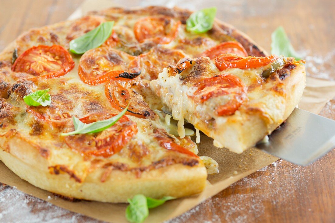 A deep dish pizza with basil leaves (Chicago, USA); one slice is on a pizza shovel