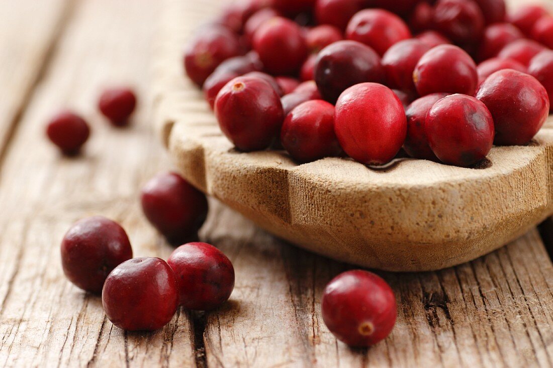Cranberries in a wooden dish on a wooden surface