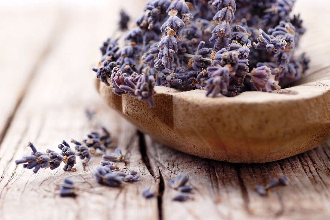 Lavender flowers in a wooden bowl on a wooden surface