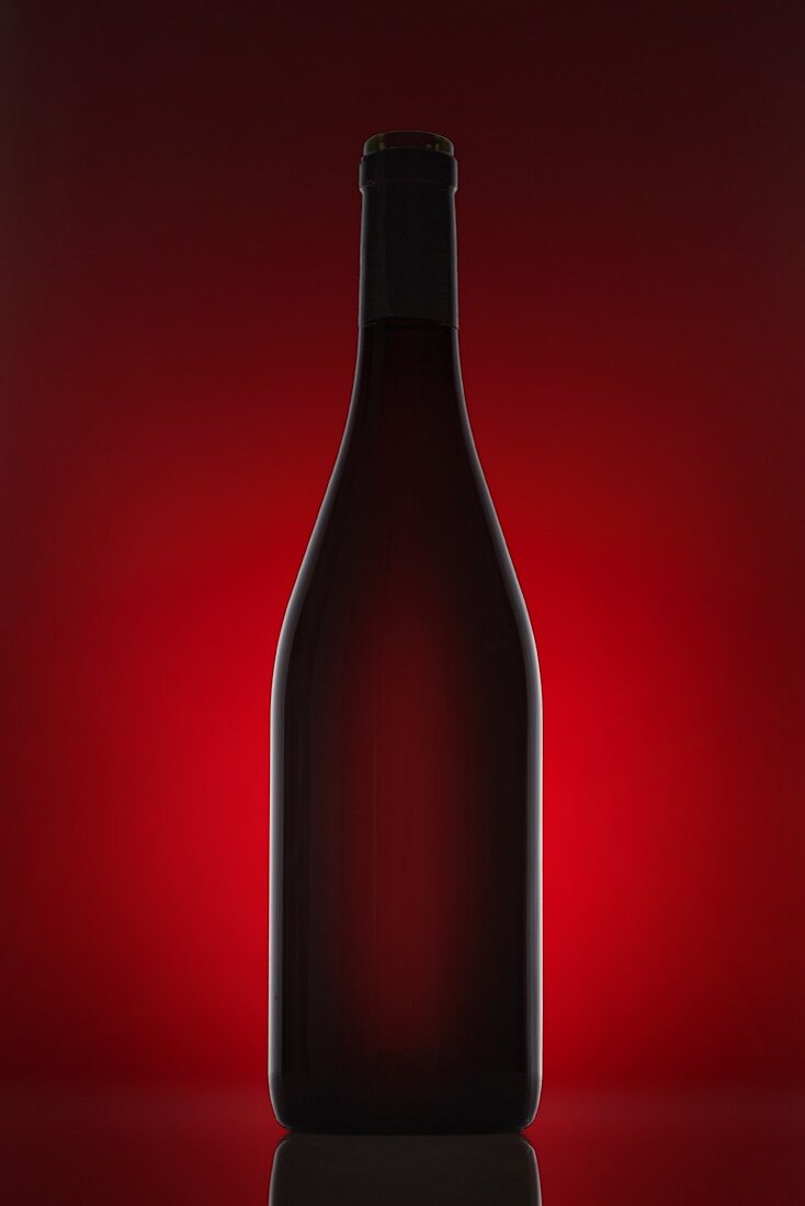 A red wine bottle against a red background