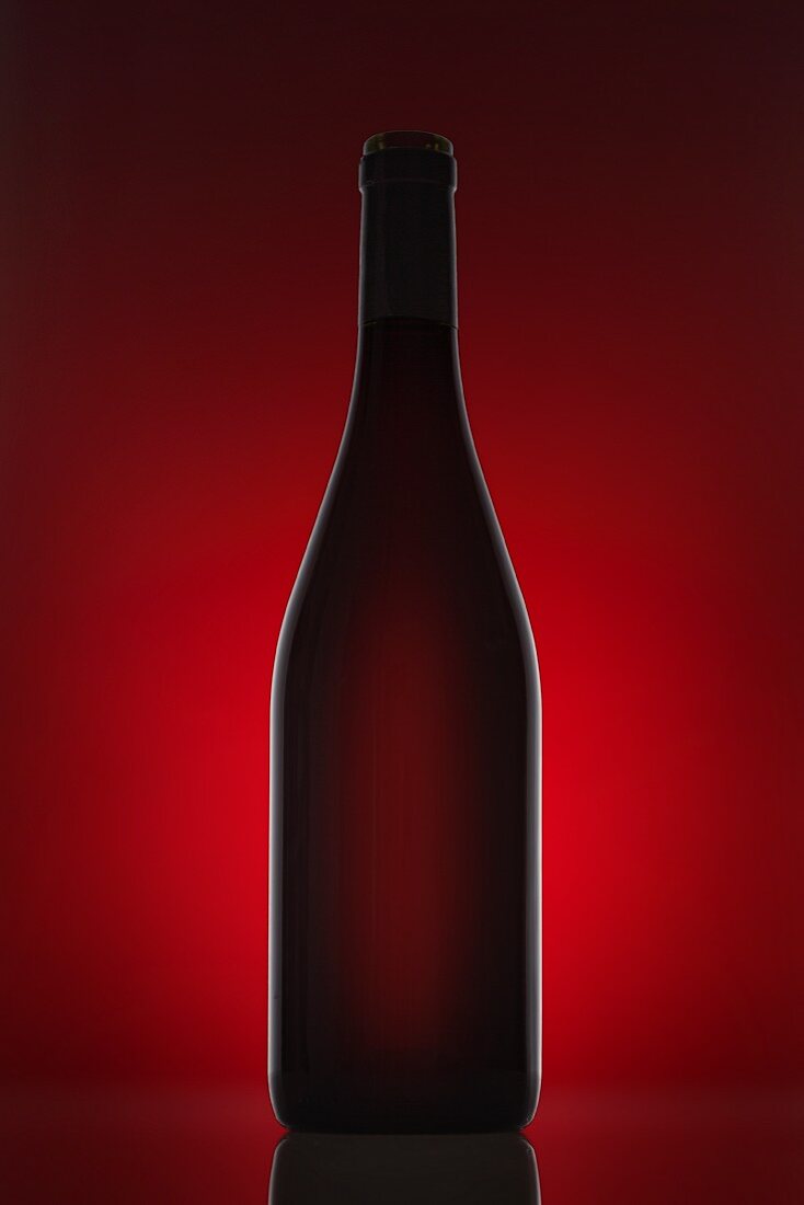 Rotweinflasche vor rotem Hintergrund
