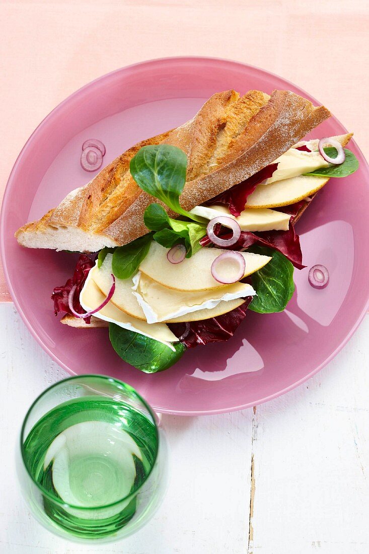 Cheese, pear slices and radicchio in a baguette, with a glass of water