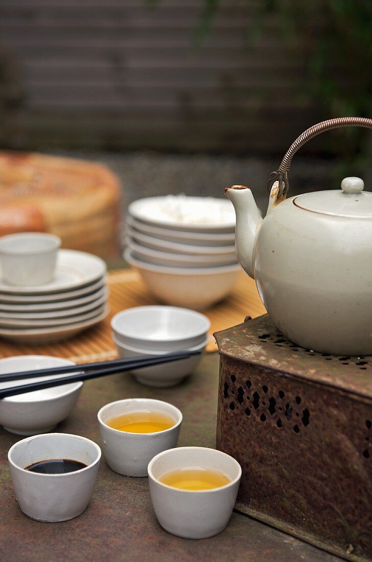 Tea bowls next to a teapot on a vintage tea warmer
