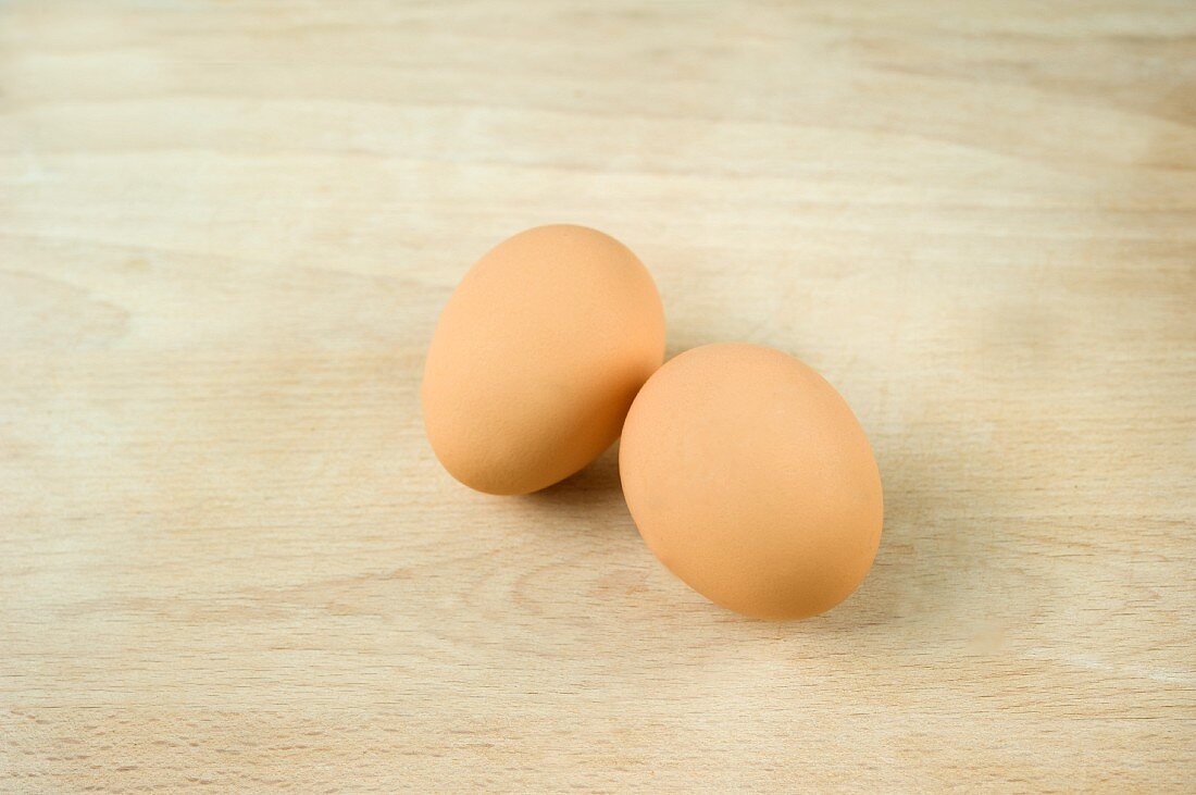 Two fresh eggs on a wooden surface