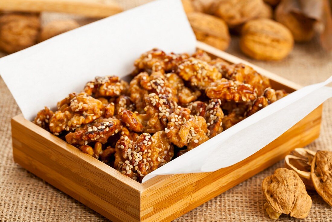 Sugared walnuts with sesame seeds in a wooden box