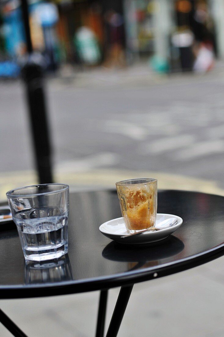 Ausgetrunkenes Kaffeeglas auf einem Tisch im Strassencafe
