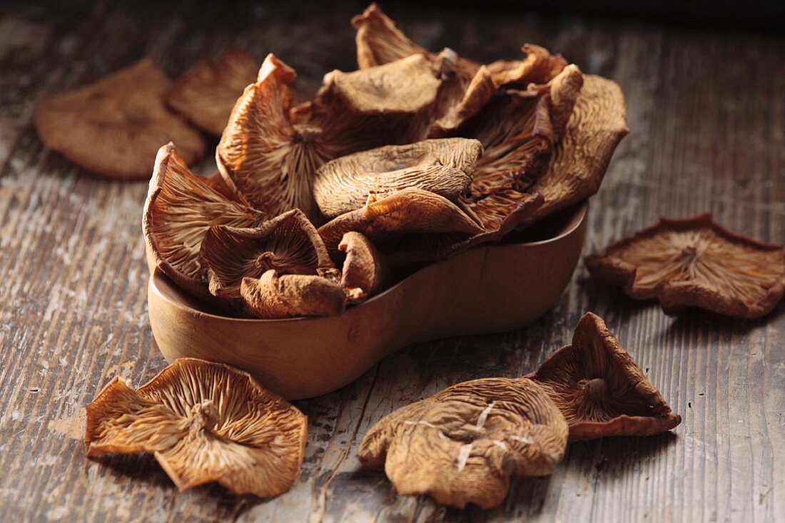 Dried honey fungus in a wooden bowl on a wooden surface
