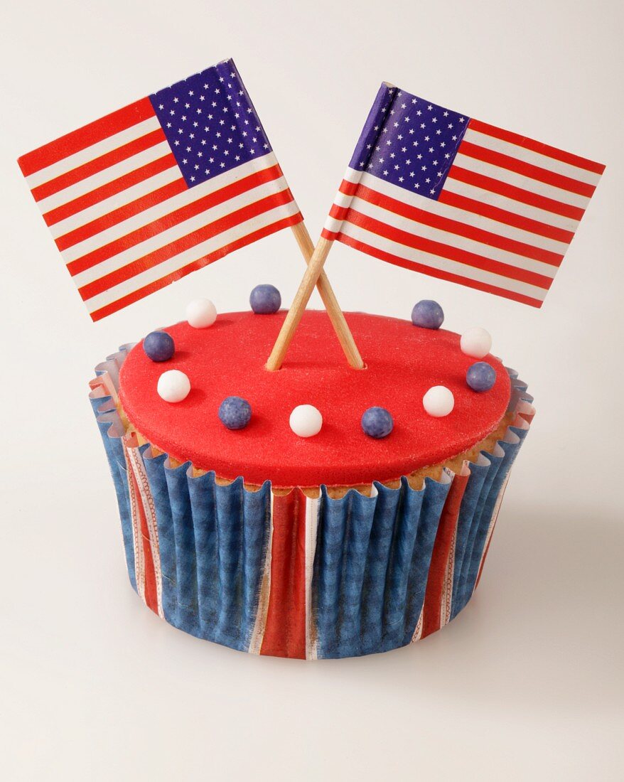 A cupcake decorated with red glaze and US flags