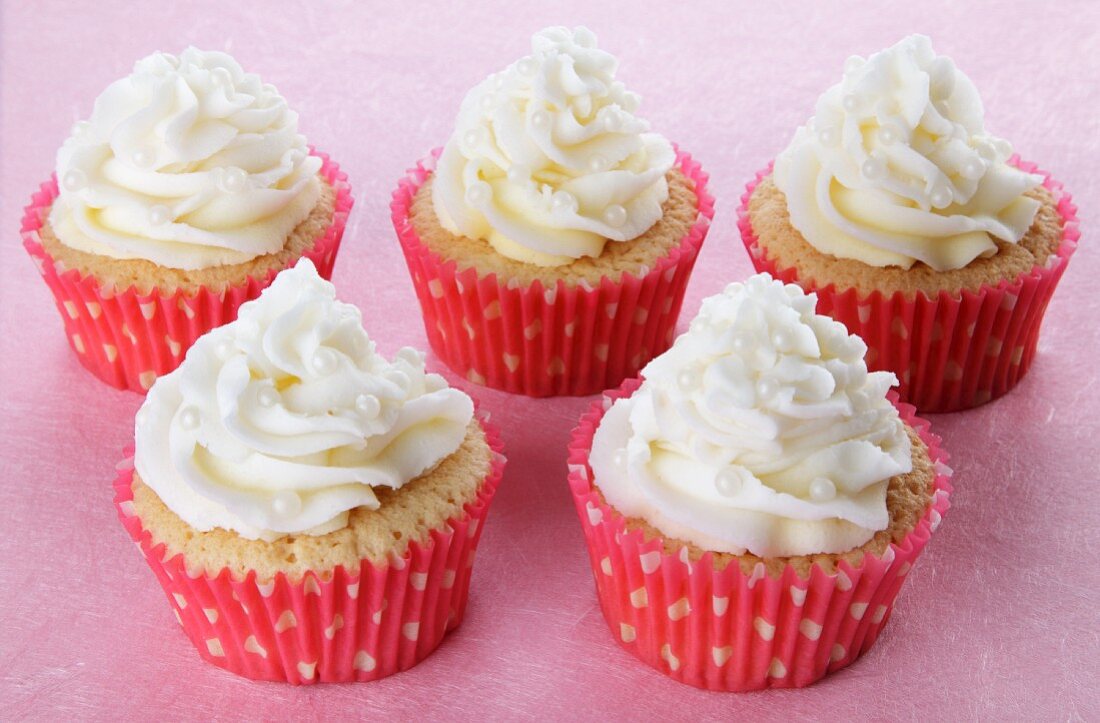 Cupcakes topped with whipped cream and small sugar pearls