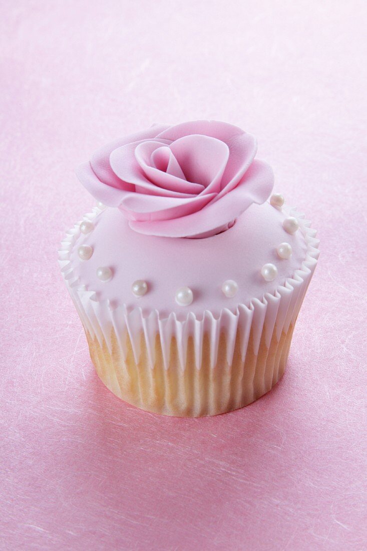 Cupcake mit rosa Glasur, Zuckerrose und Perlen