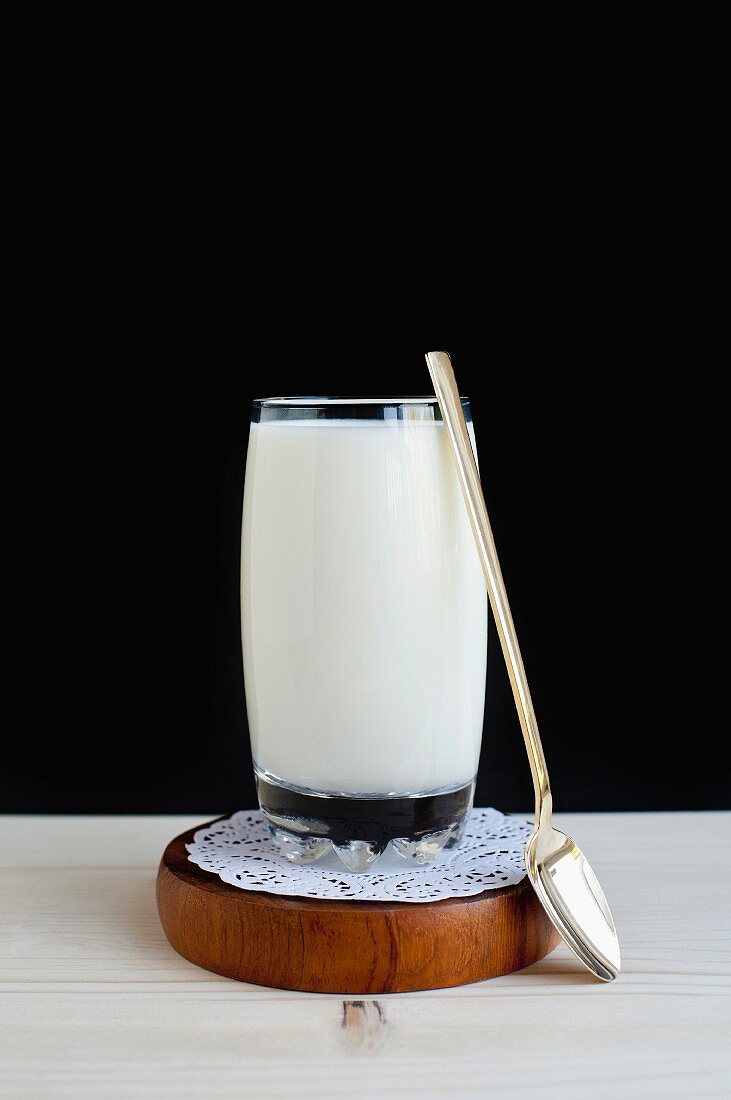 Ein Glas Milch mit Löffel auf Tortenspitze