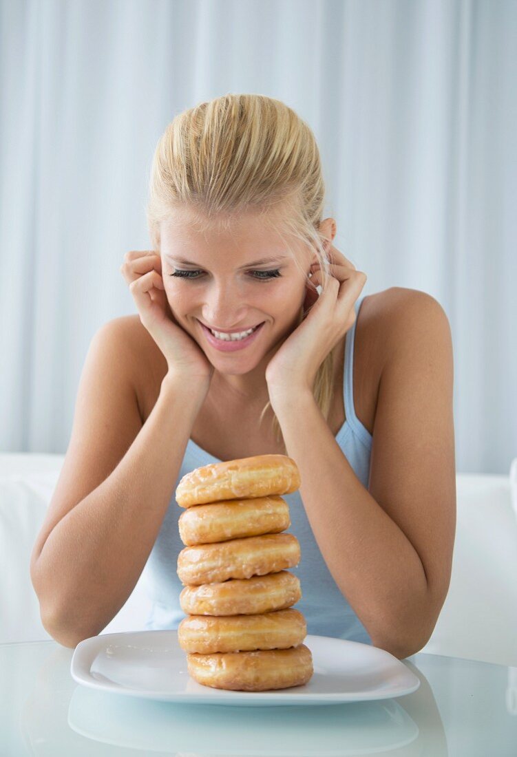 Blonde Frau schaut auf einen Stapel Doughnuts