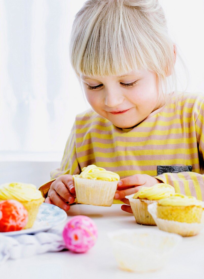 A smiling girl admiring cupcakes