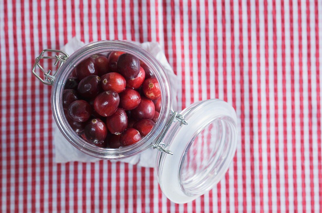 Cranberries im Einmachglas auf kariertem Tischtuch